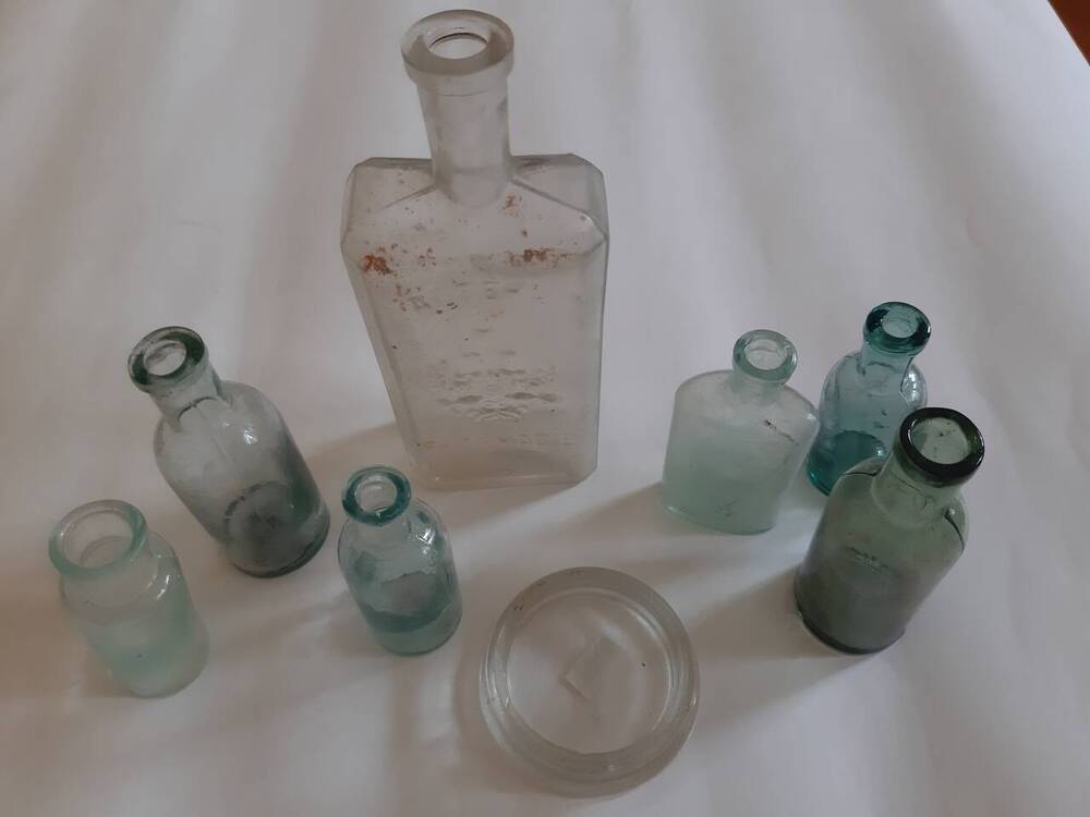 Аптекарская стеклянная круглая бутылочка из прозрачного стекла светло-зелёного цвета, с конусообразным горлышком для лекарственных средств. Без клейма, маркировки и без надписей. Без пробки. Край донышка отбит, имеется деформация. Набор аптечных провизорских бутылочек (пузырьков) периода начала 1900-х - 1940-х гг. (для микробиологических исследований), 8 шт.