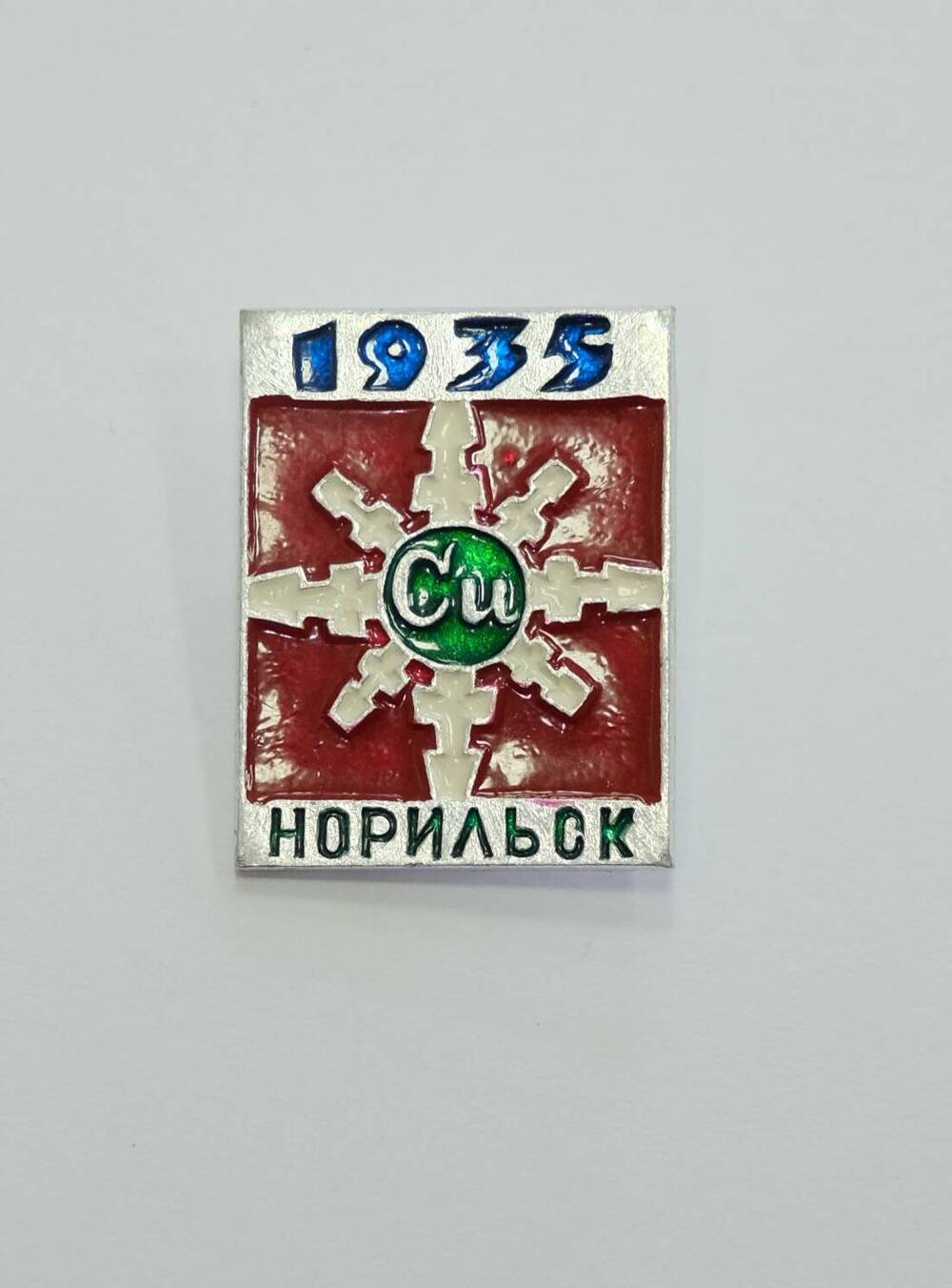 Значок СССР квадратной формы  1935 НОРИЛЬСК. На фоне красной эмали беля 8-и угольная снежинка в центре знакэлемента меди Сu.