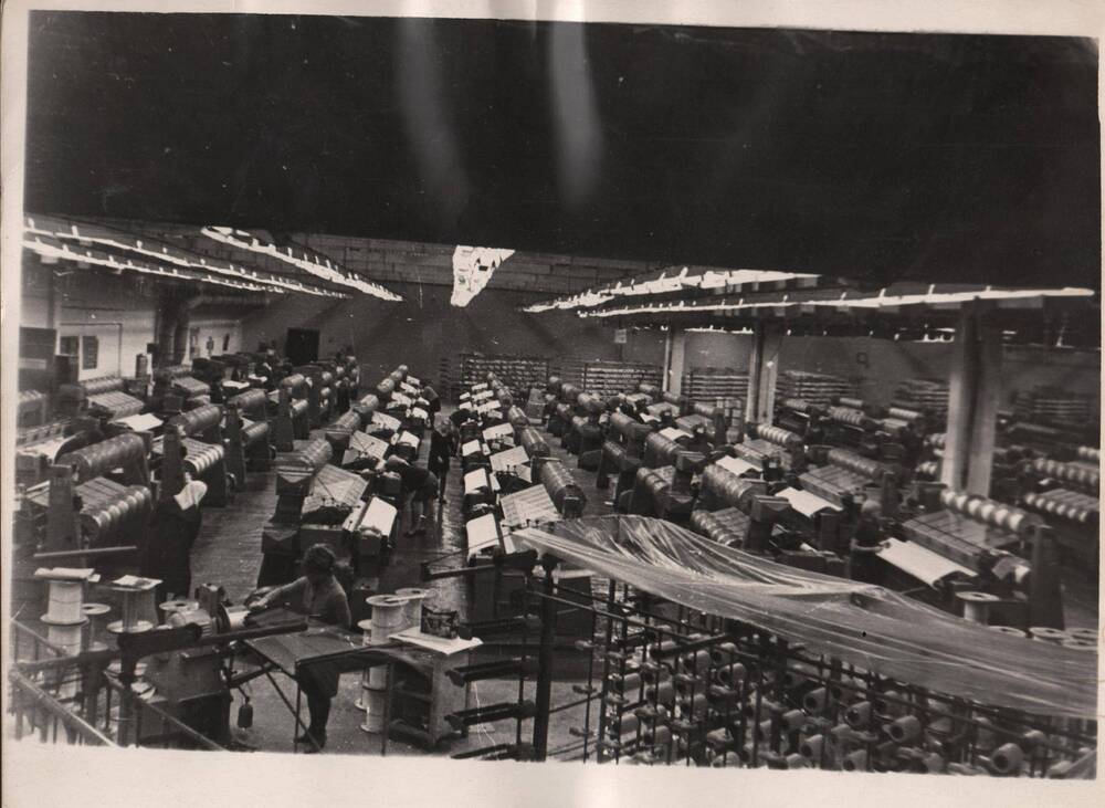 Фото вязального цеха трикотажной фабрики за работой. Снимок сделан сверху, виден почти весь цех.