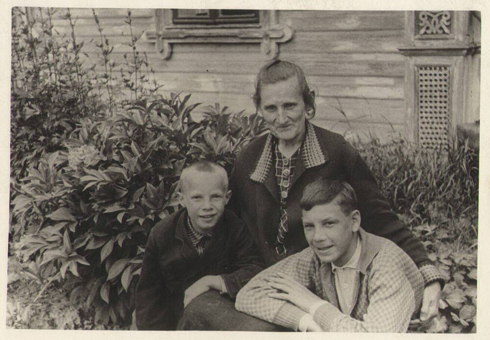Фото. Н.Г. Чкалова - мать Валерия Павловича в цветнике около своего дома с внучатами  Ю. Фролищевым и К. Гордеевым.
