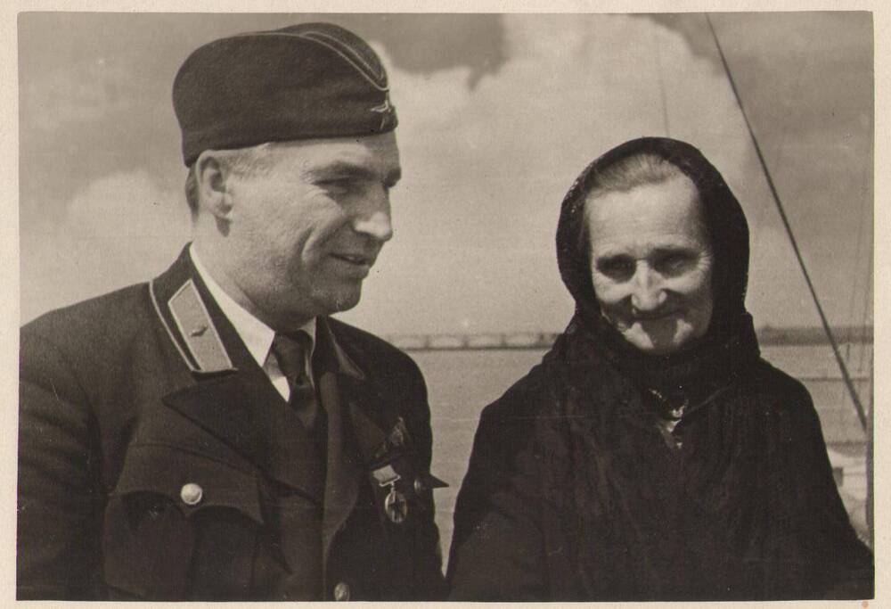 В.П. Чкалов в военной форме с орденами и пилотке стоит на борту парохода рядом со своей матерь. Натальей Георгиевной.