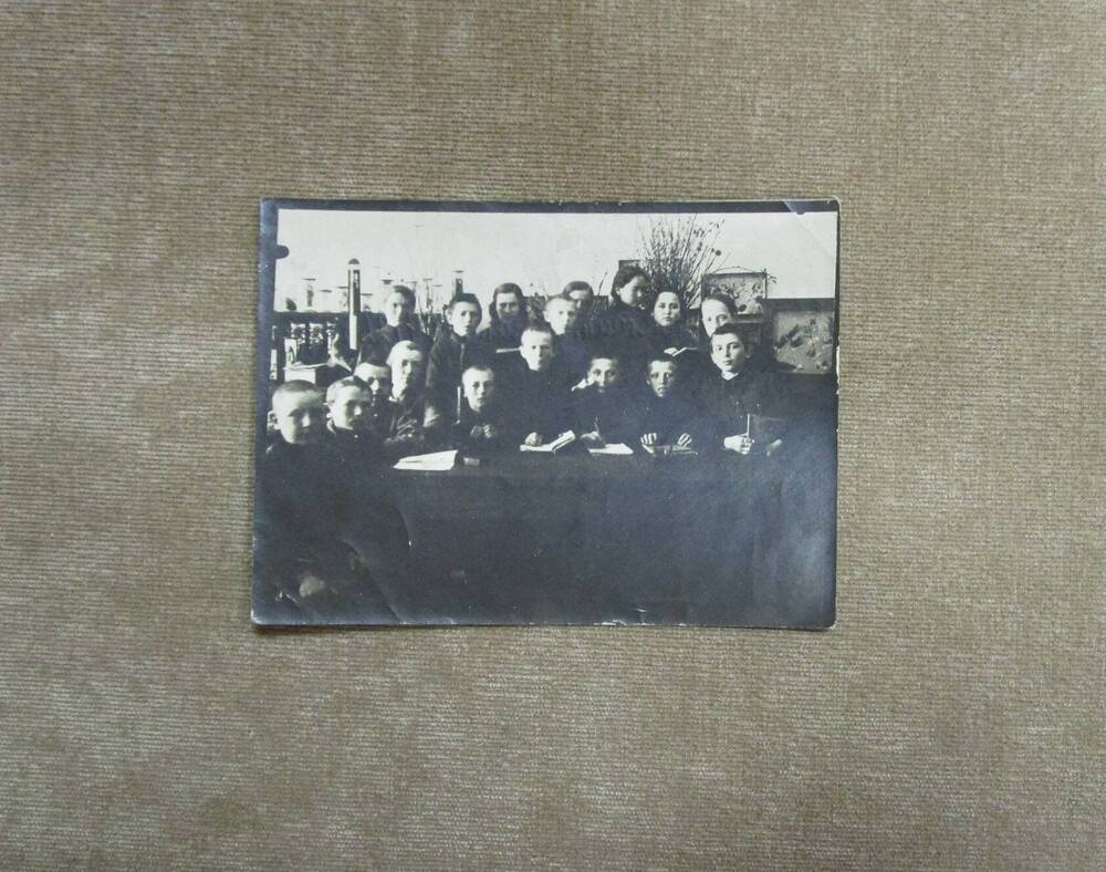 Фотография групповая детей: сидят и стоят за столом в 2 ряда с тетрадями и учебниками. На стене коробки с гербариями. Башкирия г. Стерлитамак. 1926 год.