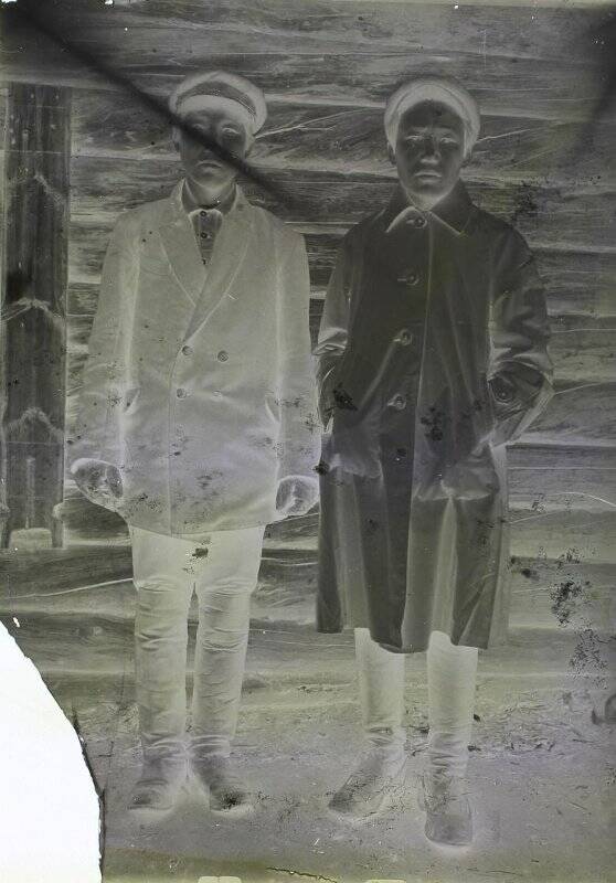 Фотопластинка. Фотопластинка с негативным изображением. На снимке изображены двое мужчин, стоящих на фоне стены деревянного дома.