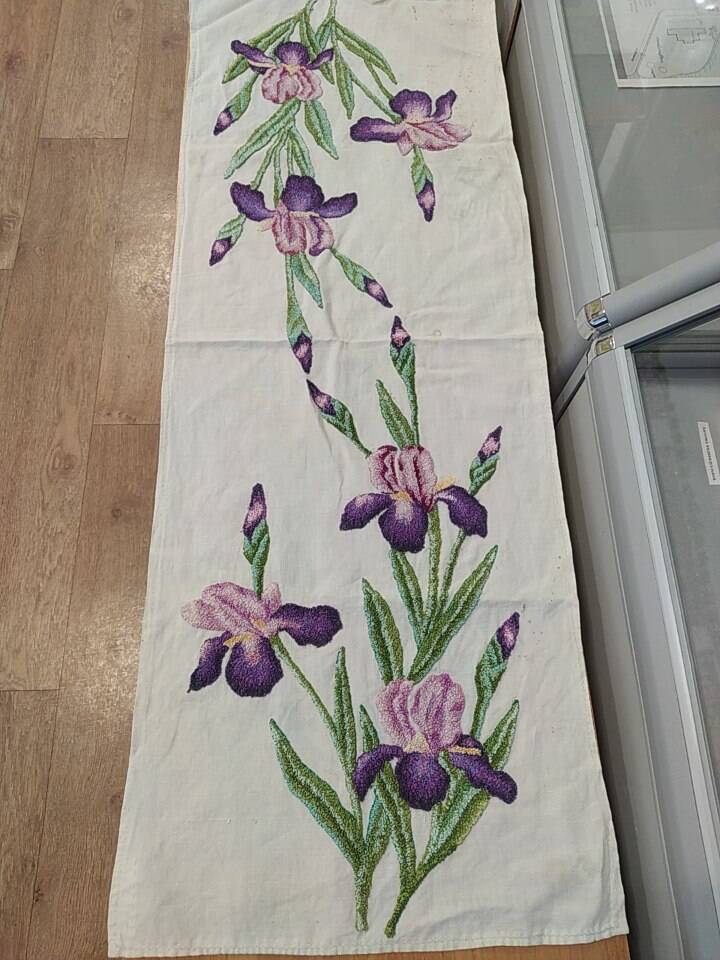 Вышивка с изображением двух букетов  ирисов фиолетового цвета, выполненная на х/б ткани. Изготовлена М.М. Горшковой в 1990г.