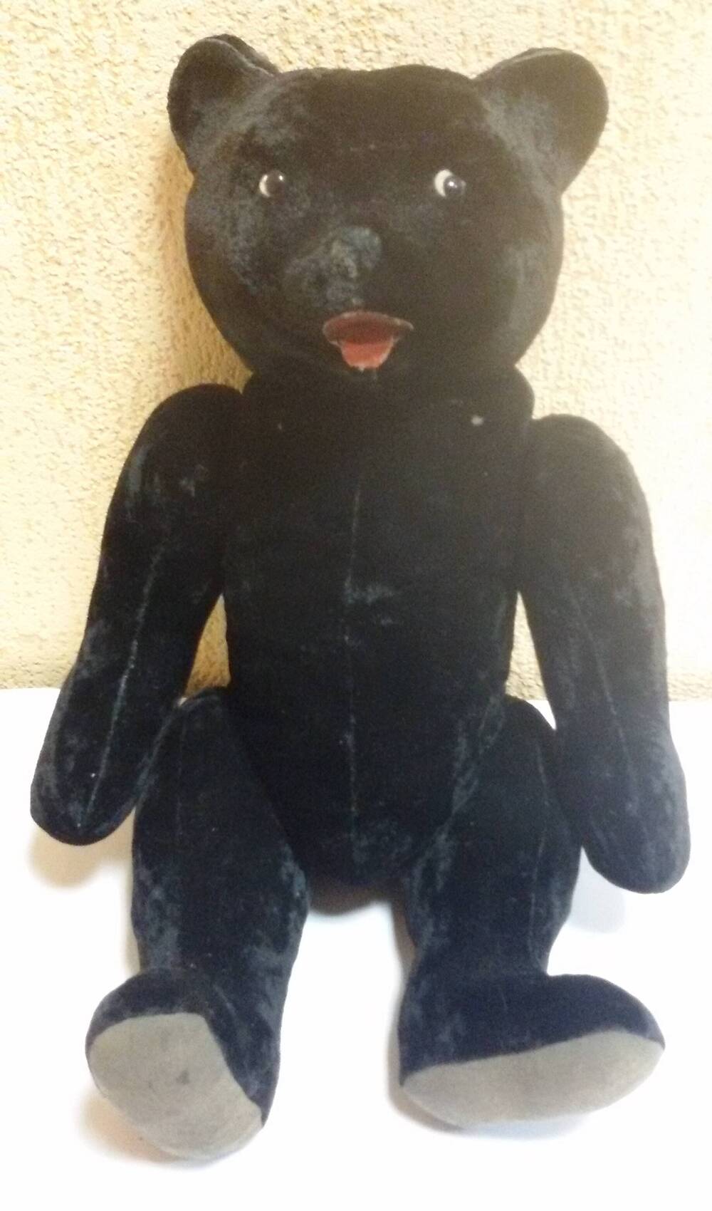 Игрушка Медведь плюшевый черного цвета, 1961 год. Лапы подвижные, 2 черных пластиковых глаза на тканевой основе белого цвета. Рот и язык из двух деталей красного цвета клеенчатые на тканевой основе.