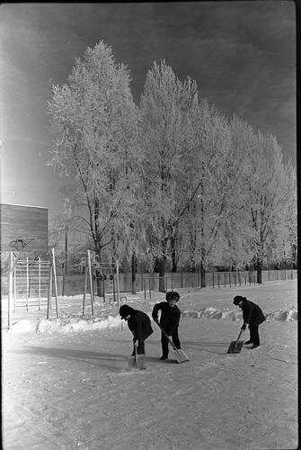 Негатив. В кадре мальчики чистят снег на спортивной площадке.