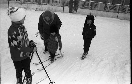 Негатив. В кадре пожилая женщина учит ребенка кататься на лыжах