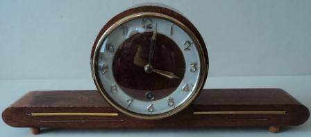 Часы настольные или каминные, механические с заводом в круглом деревянном корпусе на подставке в виде бруса