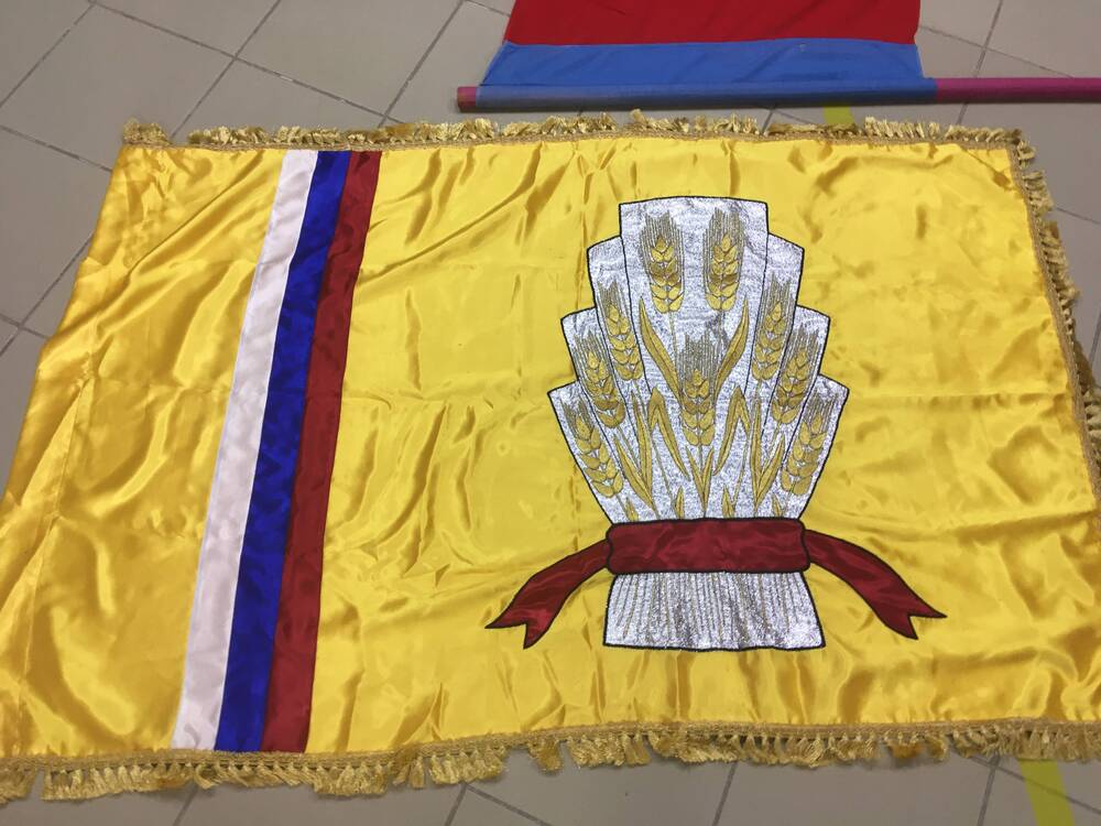 Первый флаг Адамовского района – на желтом шелке серебристый сноп, сбоку триколор, желтые кисти по краям. Впоследствии был утверждён другой