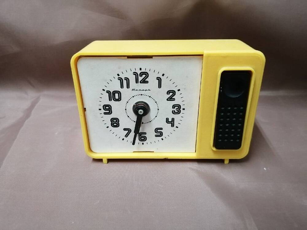 часы будильник прямоугольной формы. желтого цвета