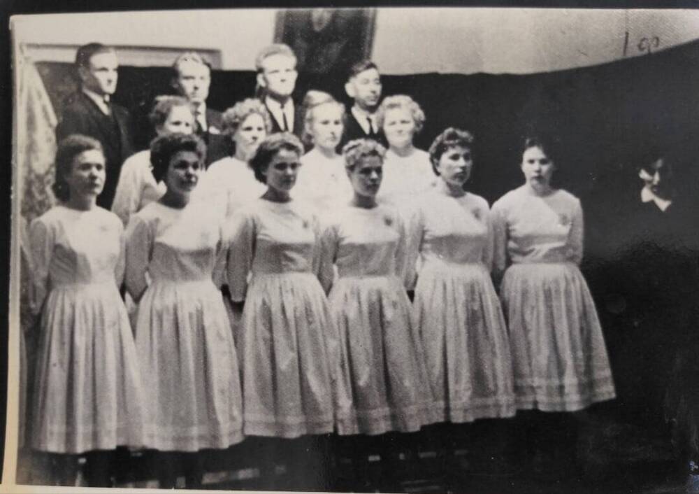 На снимке хор АЗПМ. На снимке изображены девушки в белых платьях в три ряда.