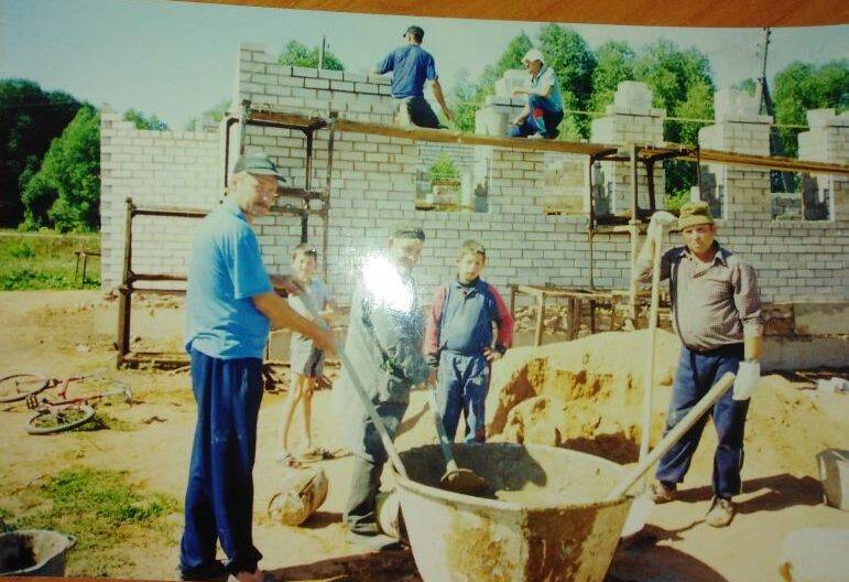 Фотография. Группа мужчин замешивают цементный раствор