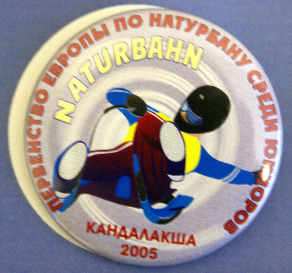 Значок памятный круглой формы «Первенство Европы по натурбану среди юниоров» с символическим изображением спортсмена-саночника.