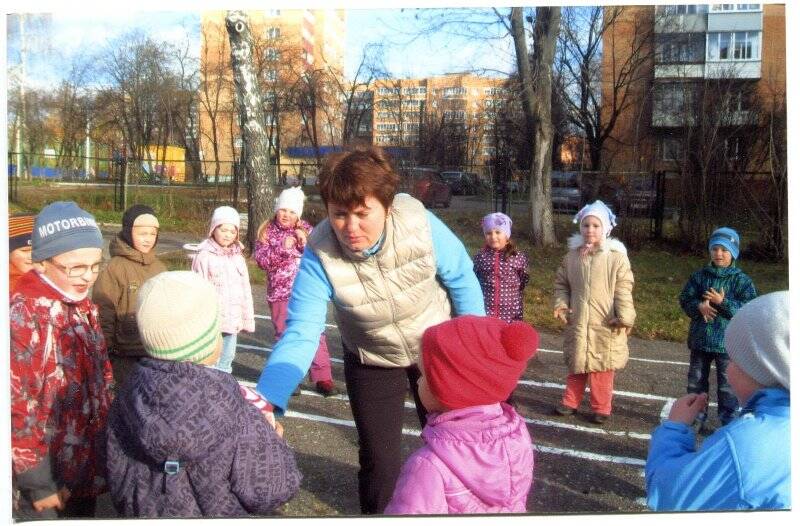 Фотография. Воспитатель Е. Журавлева проводит с подготовительной группой детского сада № 24 утреннюю зарядку на свежем воздухе.