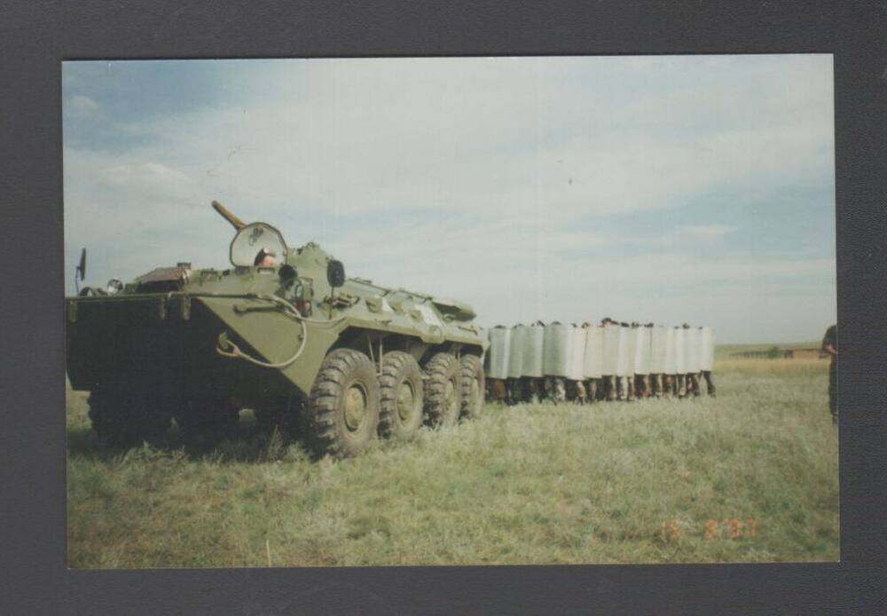 Фотография - сюжетный цветной снимок. На переднем плане БТР, сзади группа военно-служащих с металлическими щитами Учения. Чечня. Северный Кавказ.