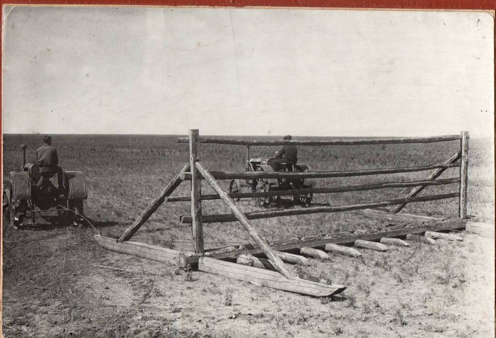 Фотография двух тракторов, тянущих самодельную волокушу.