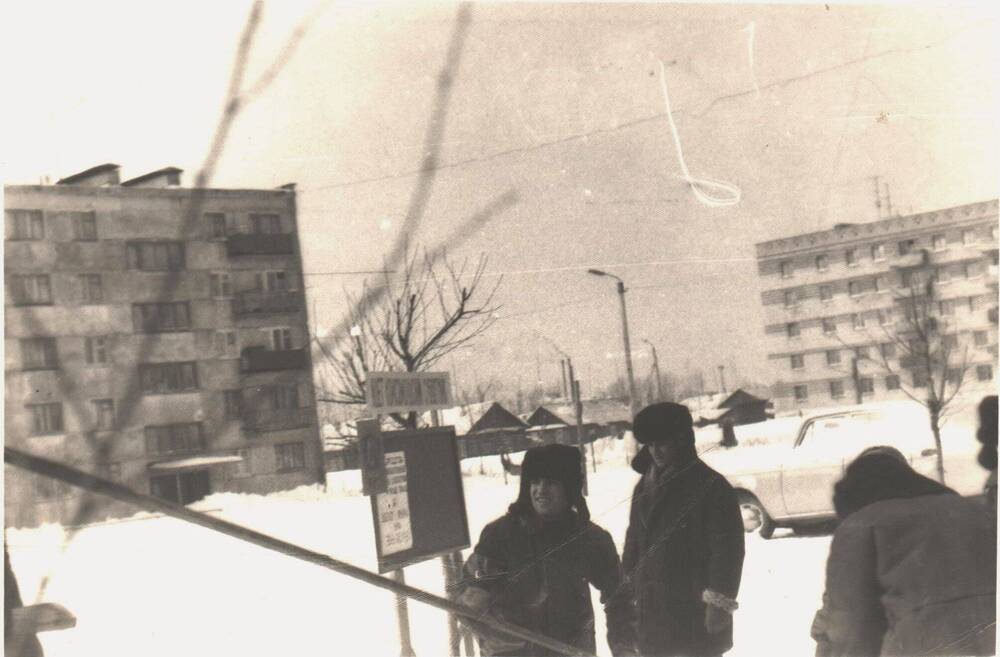 Группа мужчин стоят во дворе дома по улице Пионерской в зимнее время.
