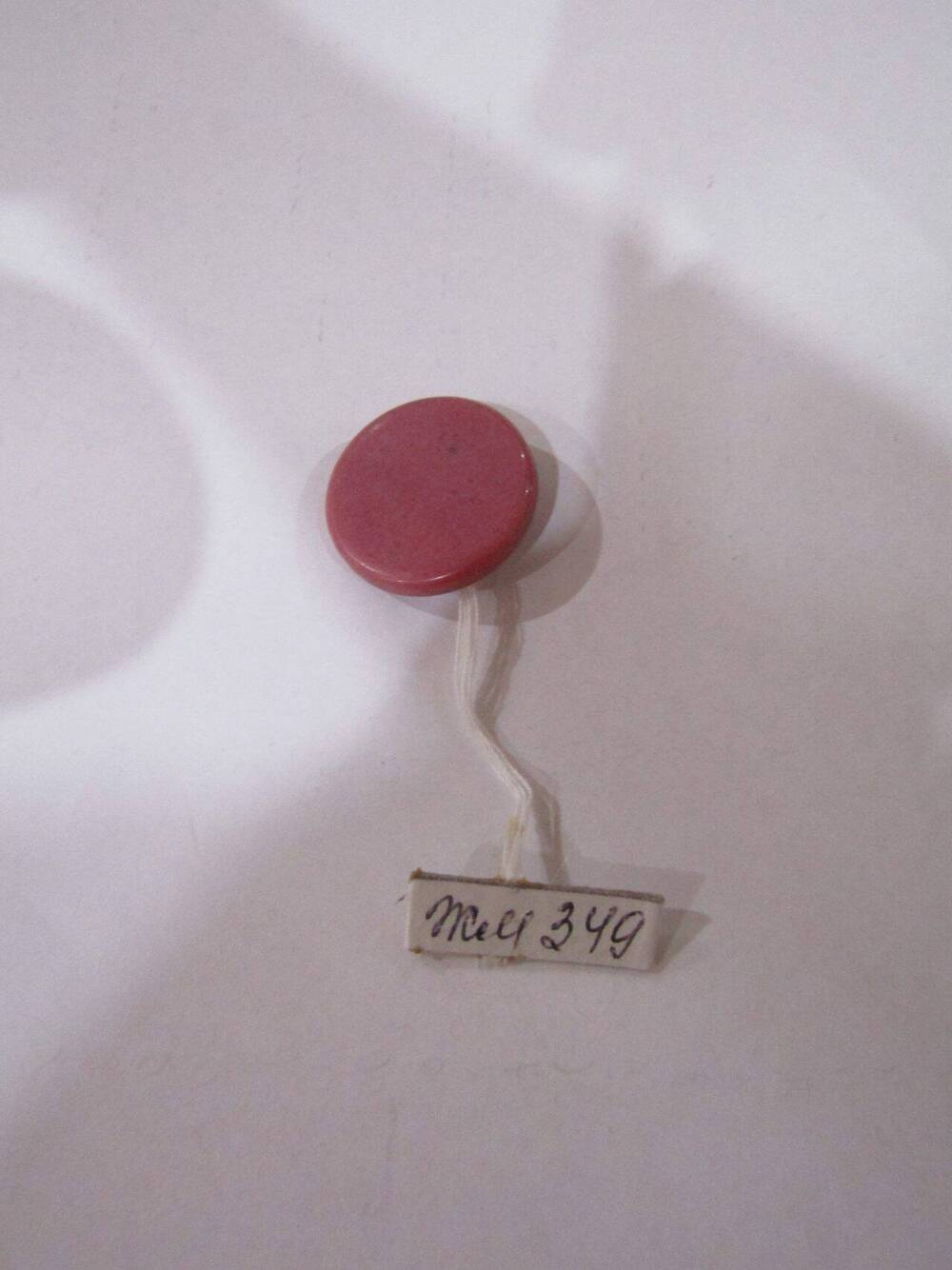 Пуговица круглой формы, темно-розового цвета
