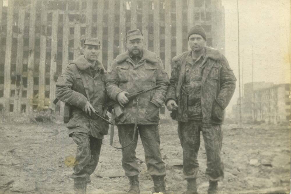 Фотография групповая. На фоне президентского здания в Чечне стоят трое военнослужащих.