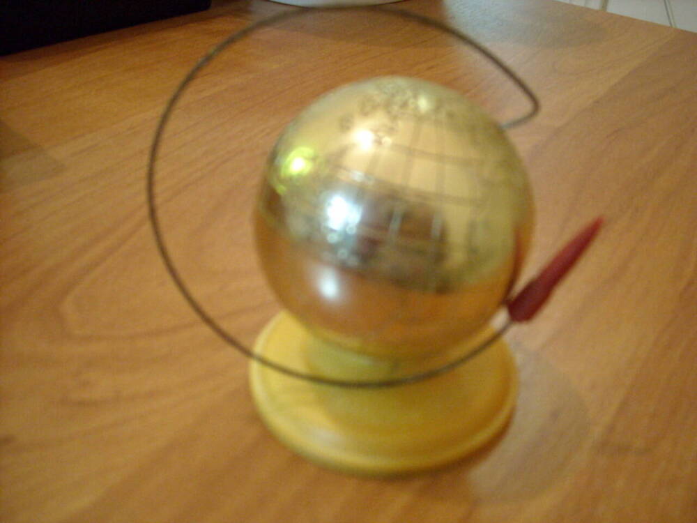 Сувенир Глобус со спутником в честь дня космонавтики. Сувенир в форме глобуса золотистого цвета, на подножке желтого цвета. На подножке надпись 12 апреля 1961. 