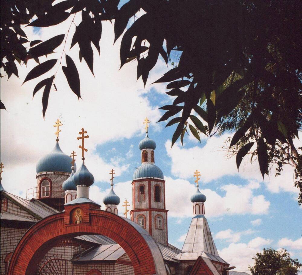 Фото цветное,горизонтальное изображение куполов Свято-Никольского храма,в обрамлении листвы деревьев,июль 1997г.