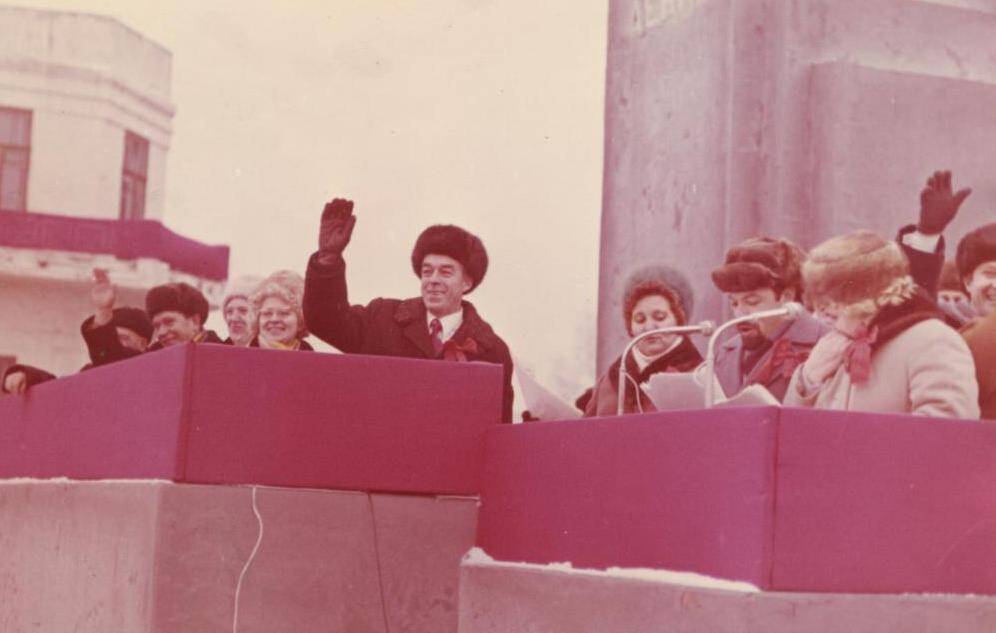 Фото чветное групповое Полнов Г.Ф. на демонстрации, стоит на трибуне ,машет рукой.