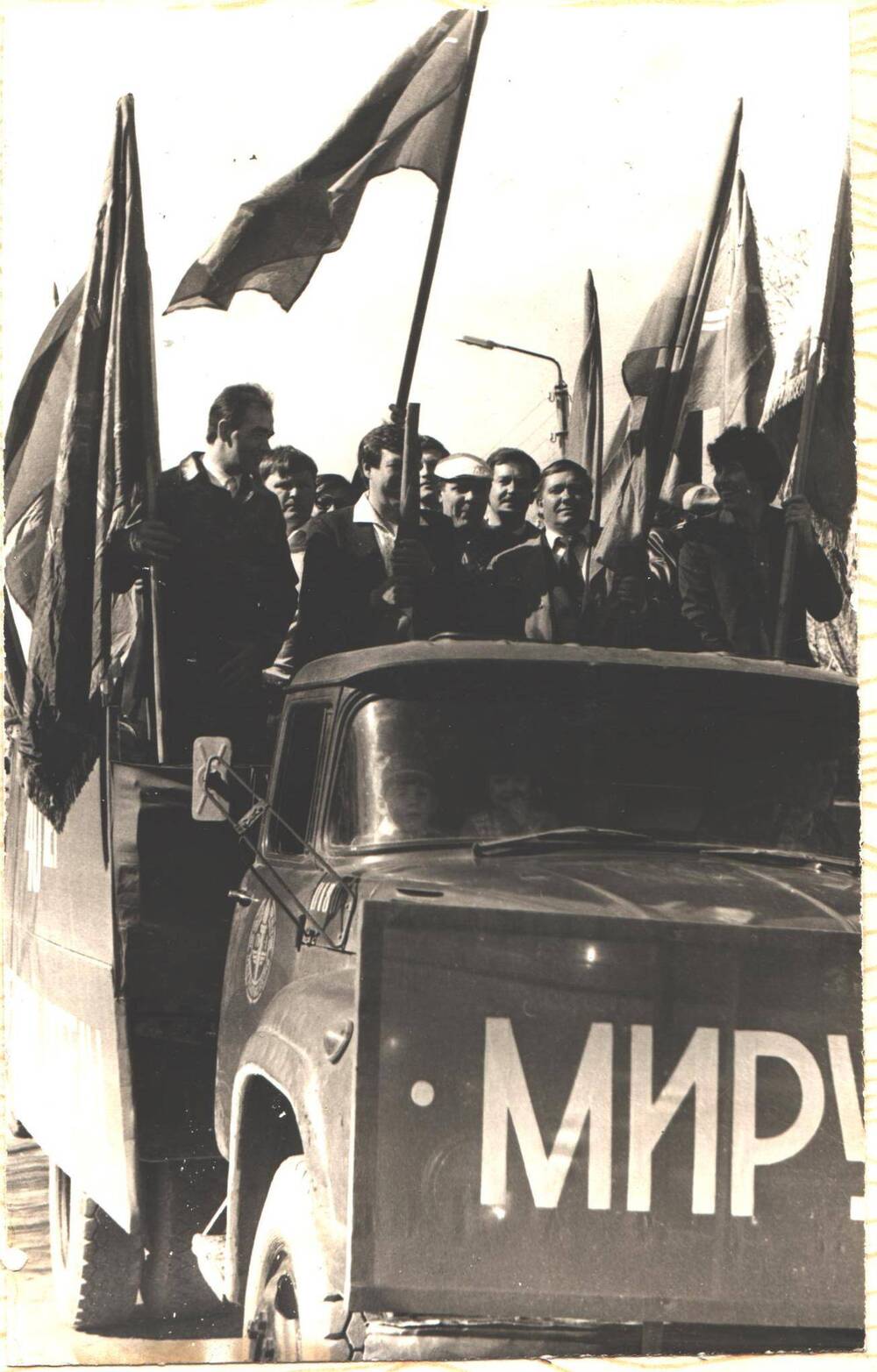 Работники КС-12 на грузовой машине с флагами едут на праздничный парад, посвященный 40-летию Победы в Великой Отечественной войне 1941-1945 годов, город Микунь.