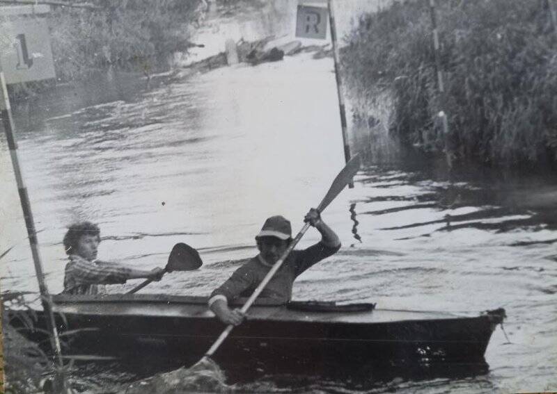 Фотография ч/б горизонтальная. На туристическом слете, двое мужчин в байдарке.