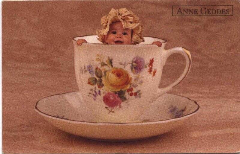 Открытка почтовая. Anne Geddes. Чайная пара из чашки выглядывает малыш в чепчике
