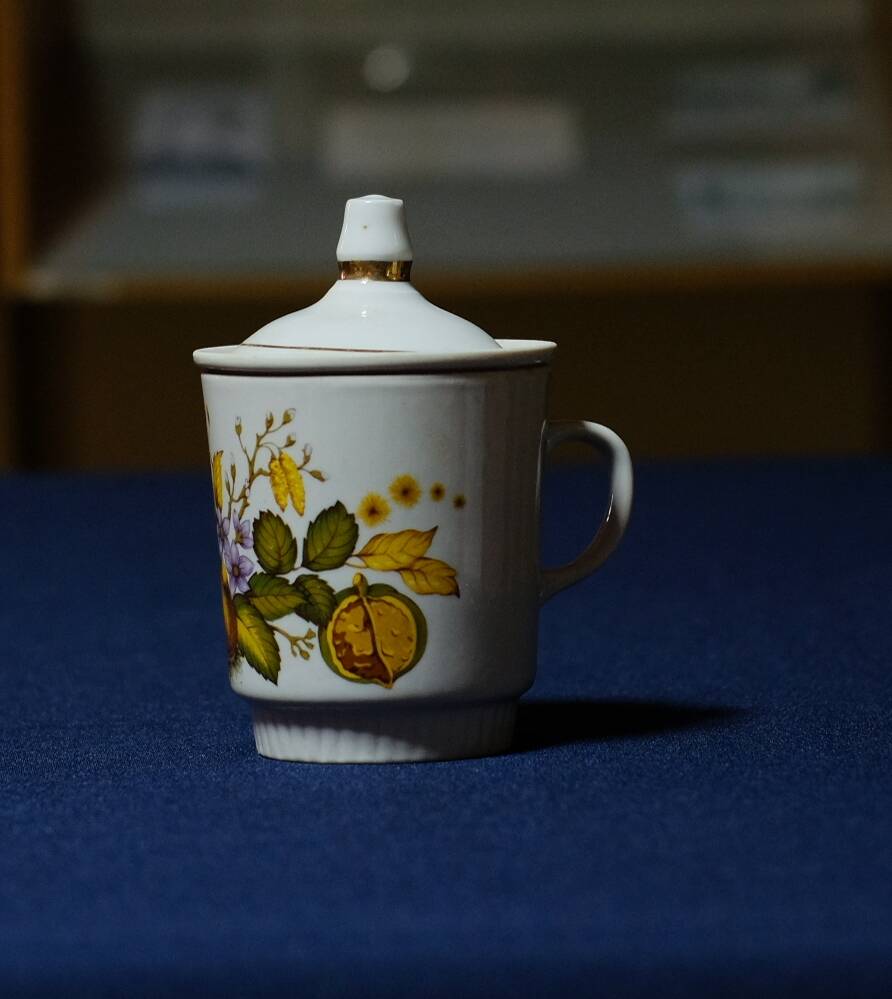 Бокал для заварки чая с коричневато-зеленым рисунком орешника и фиолетовым цветом с крышкой и вкладышем для чая.