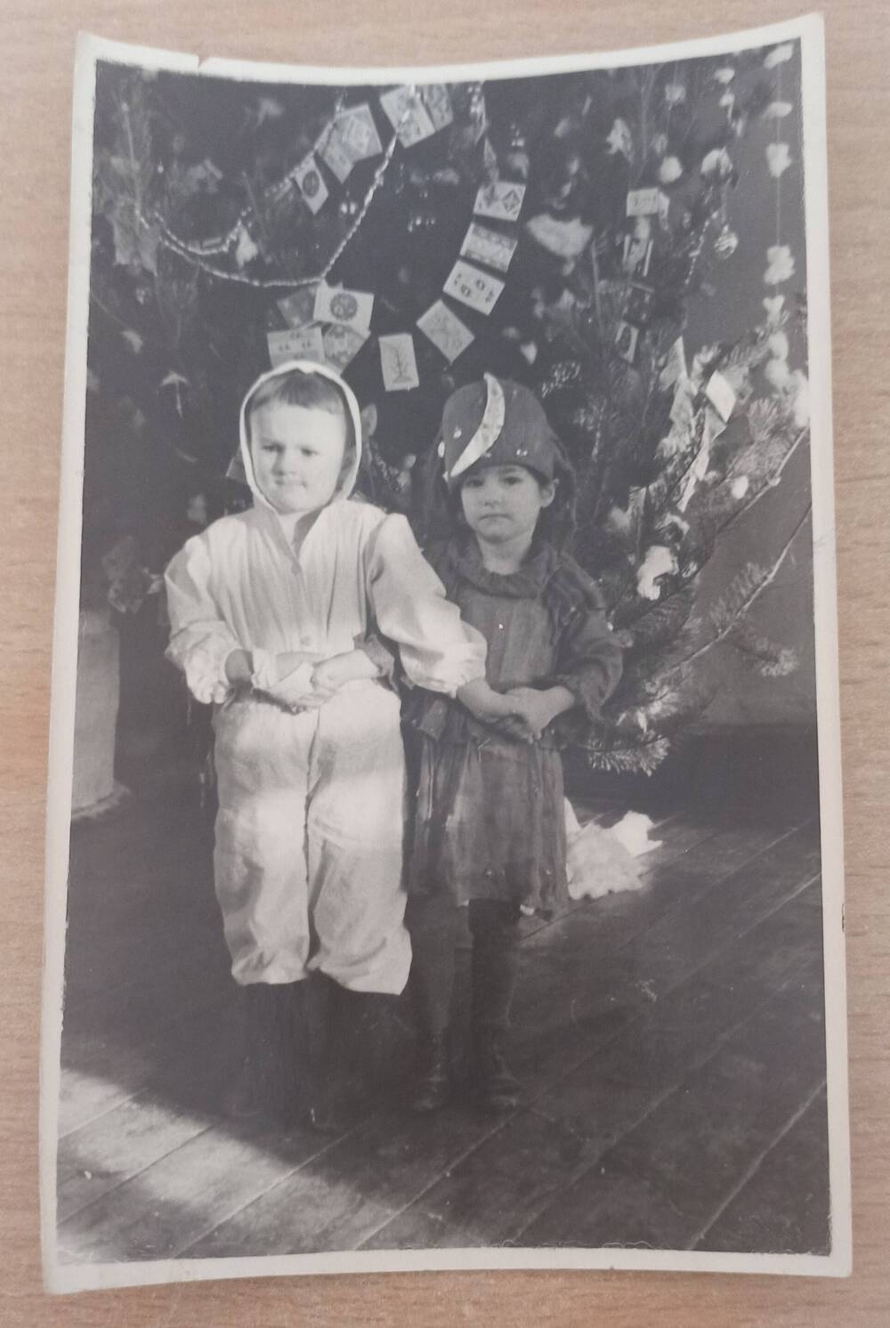 Фотография ч/б. Два ребенка в новогодних костюмах возле елки. Справа девочка в костюме ночки. Город Сковородино.