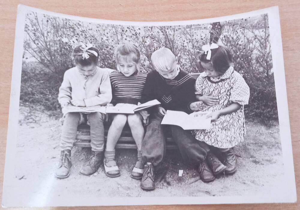 Фотография ч/б. Четверо детей дошкольного возраста на улице рассматривают книжки г.Сковородино,  детский сад в северной части города.