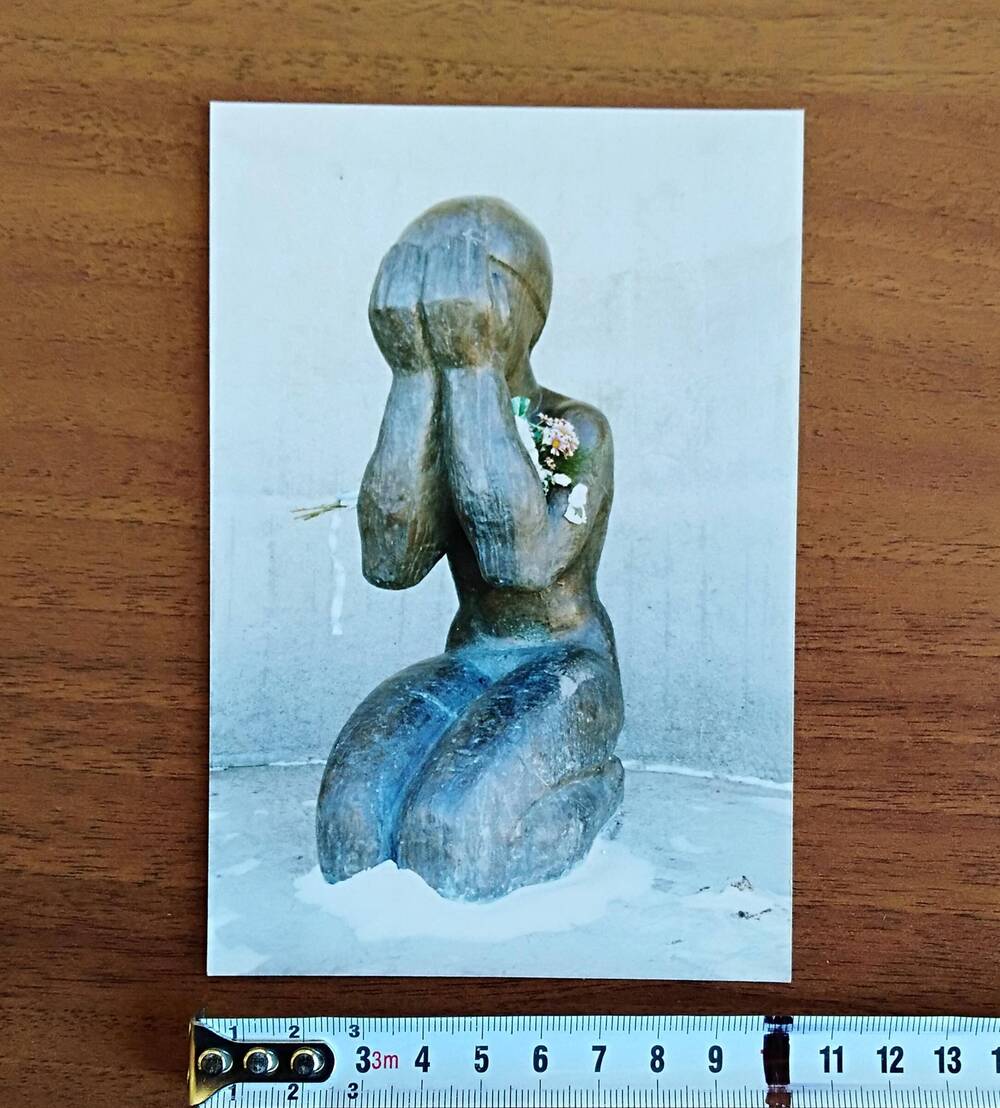Фотография цветная, глянцевая печать, скульптура молодой коленопреклоненной женщины на нижней площадке монумента «Маска Скорби» в г. Магадане, 1990-е гг.