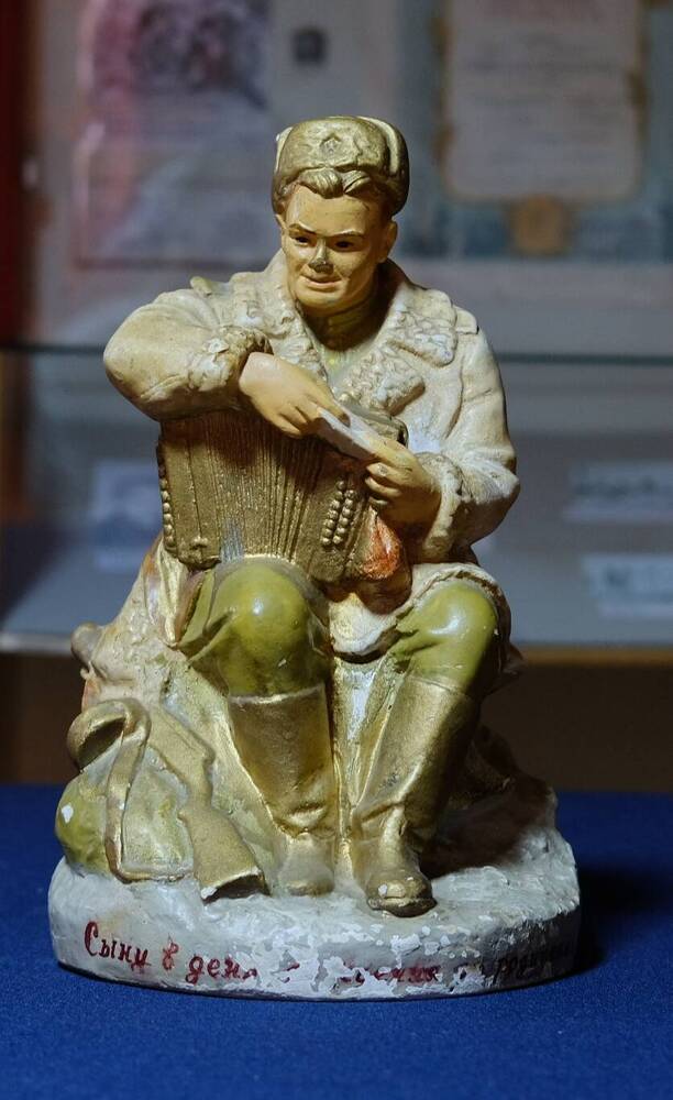 Скульптура Василий Теркин,изображен боец,сидящий на пеньке,в полушубке,шапке-ушанке с гармонью на коленях. 1965г.