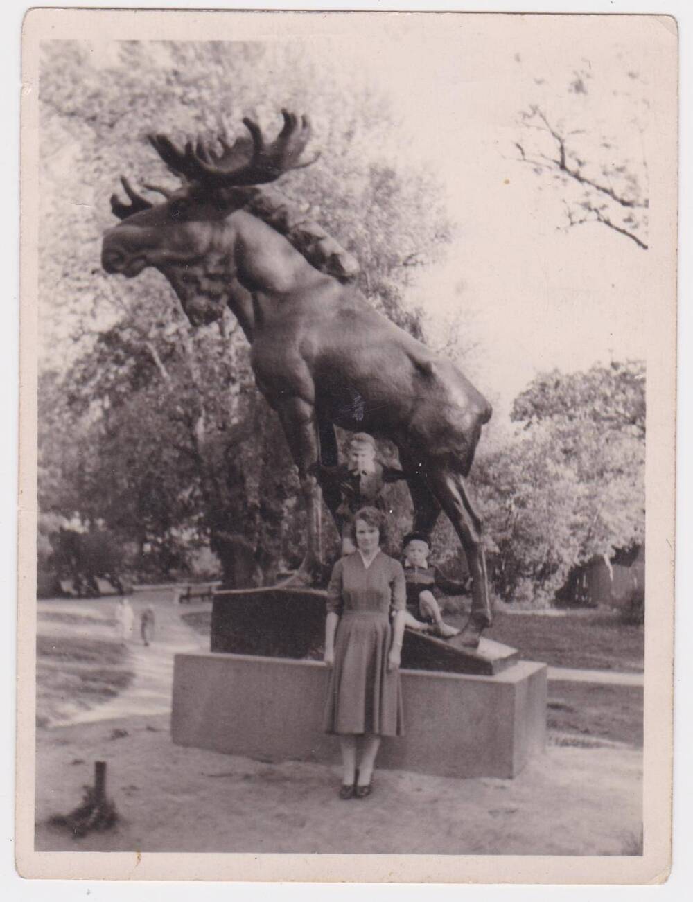 Фотография ч/б. Женщина в лёгком платье с двумя мальчиками около Лося