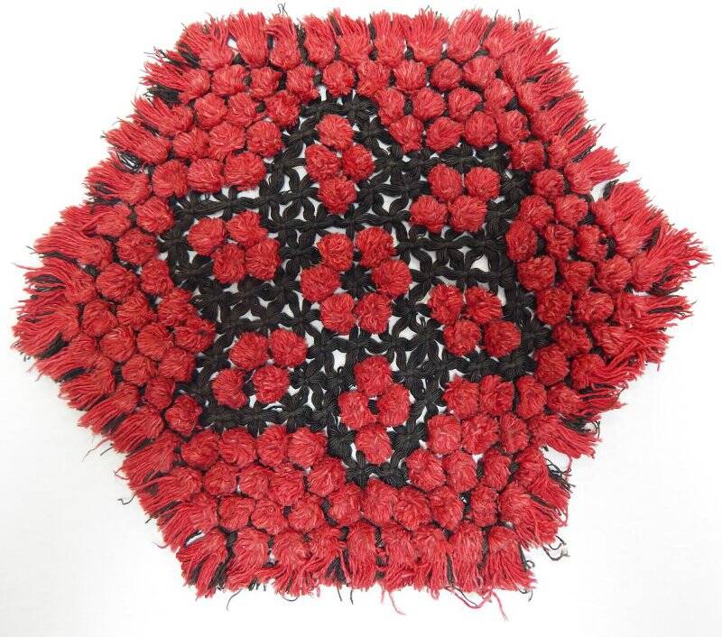 Салфетка красно-черного цвета, плетеная на шестиугольной раме в стиле тенериф, с бахромой.