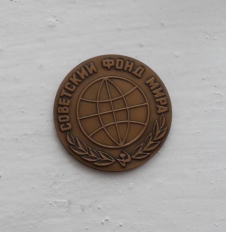 Медаль от Советского фонда мира круглой формы с рельефным изображением эмблемы Советского фонда мира. Изготовлена из сплава золотисто-коричневого цвета.