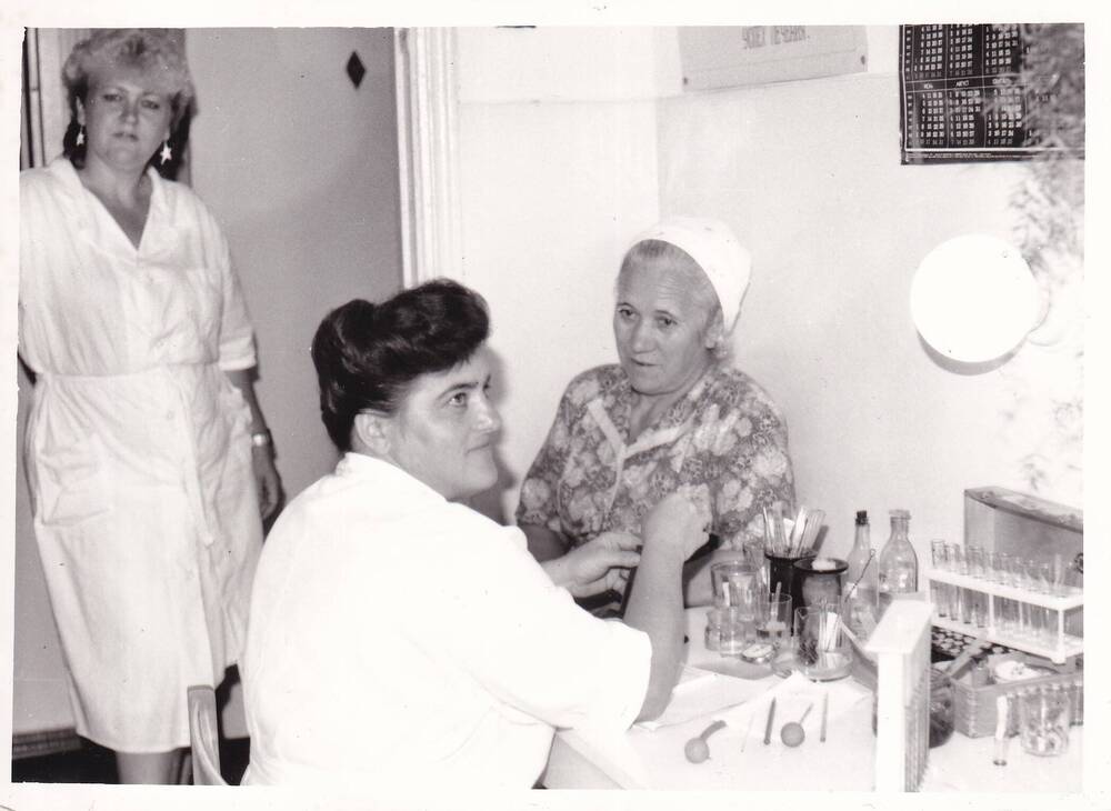 Фото ч/б групповое. Тимонина Л.И., лаборант поликлиники №2 пос. Кубрис ведёт приём. 1980-е годы.