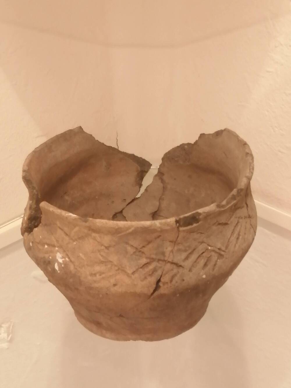 Чаша глиняная ручной лепки с вогнутой шейкой и уплощенным венчиком.  По шейке и ребру нанесен орнамент в виде горизонтального зигзага.
