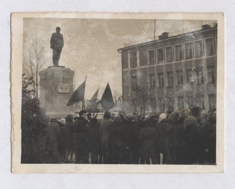 Фотография черно-белая, групповая. Изображена демонстрация у здания почты и памятнику Ленину.