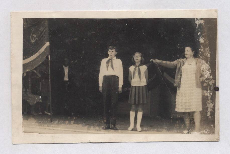 Фотография черно-белая. Изображены стоящие на сцене мальчик и девочка среднего школьного возраста, в пионерских галстуках.