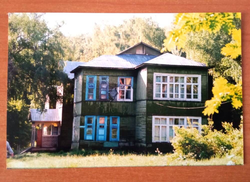 Фото цветное. На фото изображено административное здание санатория им. С. Т. Аксакова деревянное, окрашено зеленой краской. Здание запечатлено на фоне летнего пейзажа. Здание построено в 40-е гг. XX века.