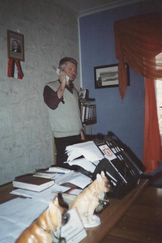 Фотография цветная. И.И. Киреев - директор музея в своем кабинете, с телефоном.