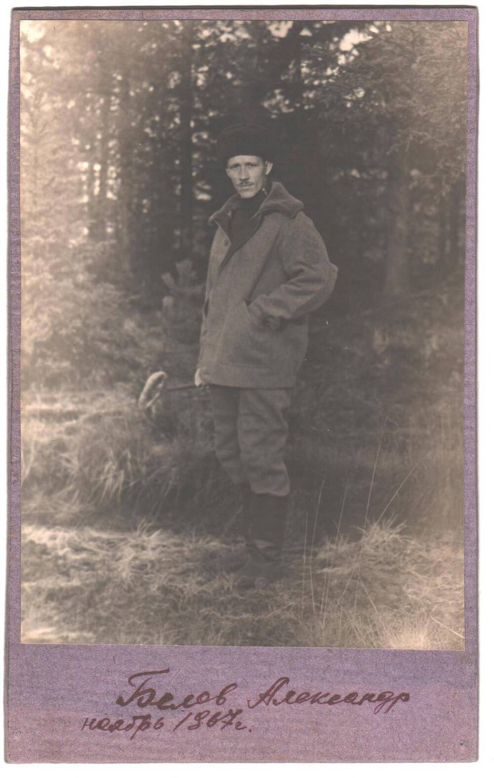 Белов Александр Ефимович  в спецодежде лесоруба, в руке держит железный крючок для откатки бревен.