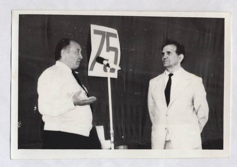 Фотография черно-белая. Изображены В.А. Нашивочников и мужчина в форме, стоящий у микрофона.