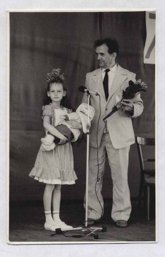 Фотография черно-белая. Изображены В.А. Нашивочников рядом с девочкой, держащей в руках куклу.