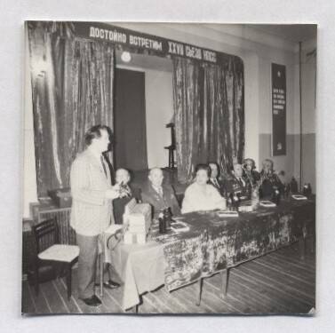 Фотография черно-белая, групповая.  Изображен стол президиума, стоящий у сцены, у которого стоит В.А. Нашивочников.