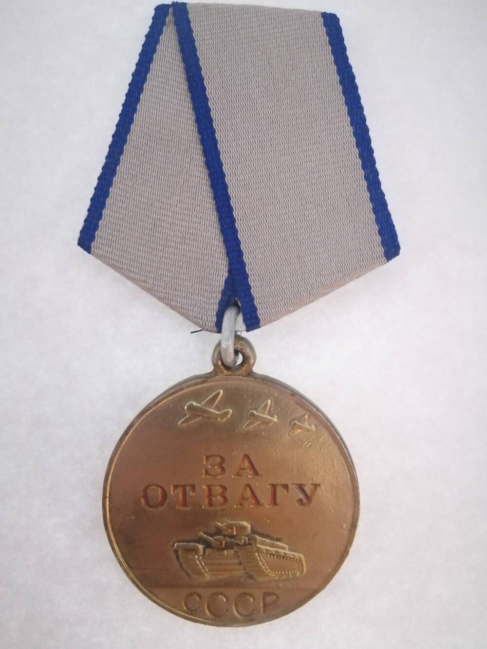 Медаль За отвагу №354520 награжденного Валиханова Ф.М. от 10.04.1954 г. На медали изображены танк и самолет и надпись красными буквами За отвагу СССР.