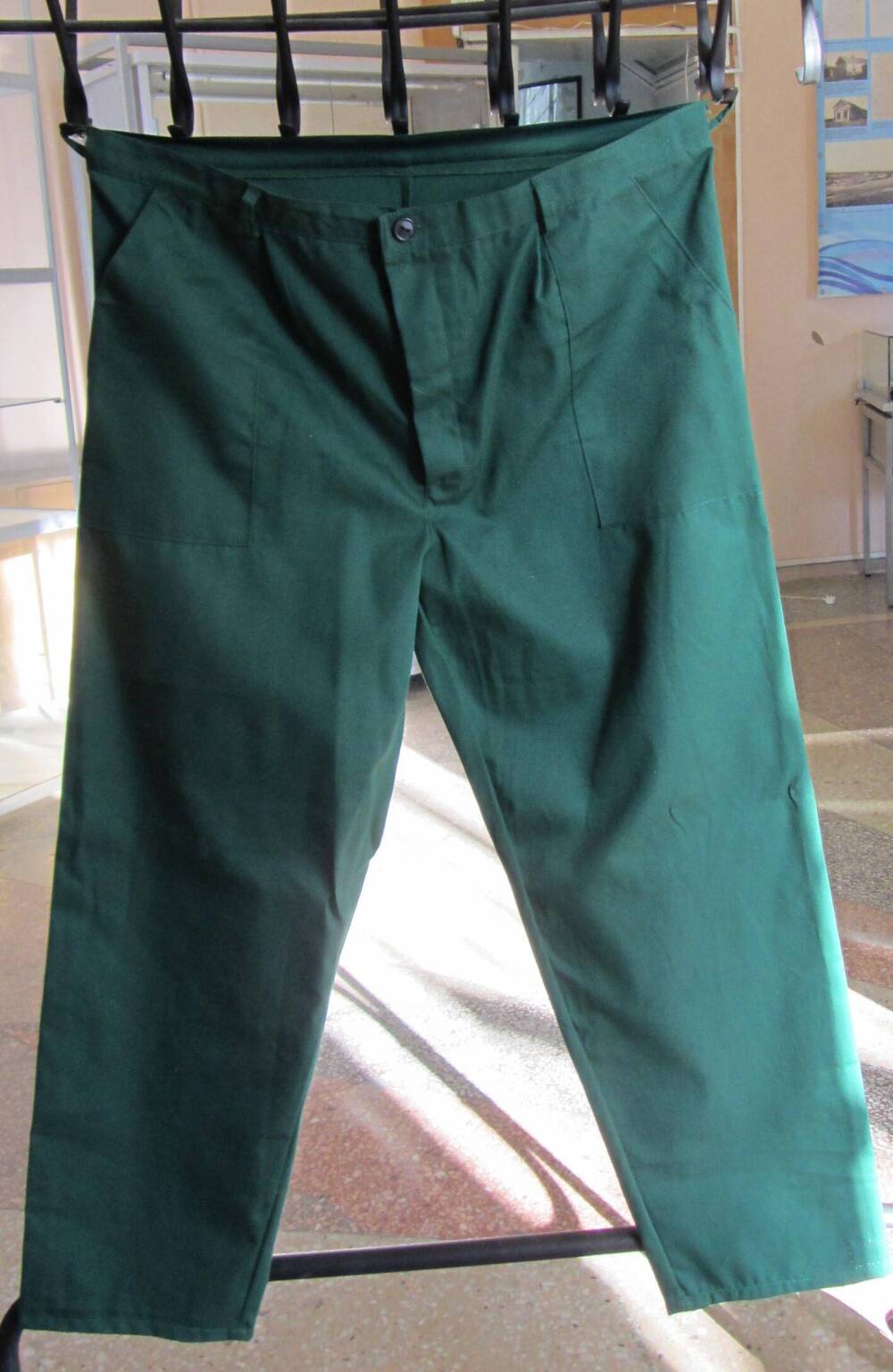 Брюки – деталь рабочего костюма ОАО «ВАТИ», с накладными карманами, с застёжкой на пуговицы, сшиты из ткани зелёного цвета.