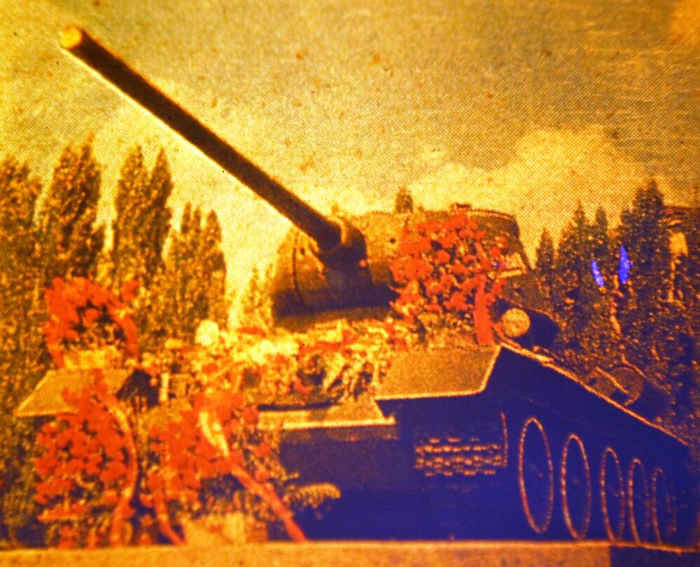Слайд пластмассовый, на котором изображен танк Т-34 с возложенными к нему цветами и венками.